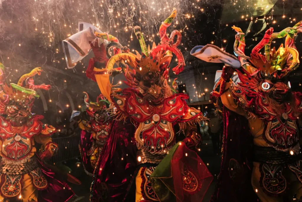 Grupo de foliões com fantasias coloridas se apresentando a noite