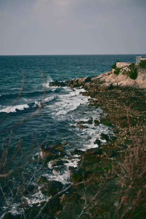 Costa rochosa com casa isolada diante do mar aberto