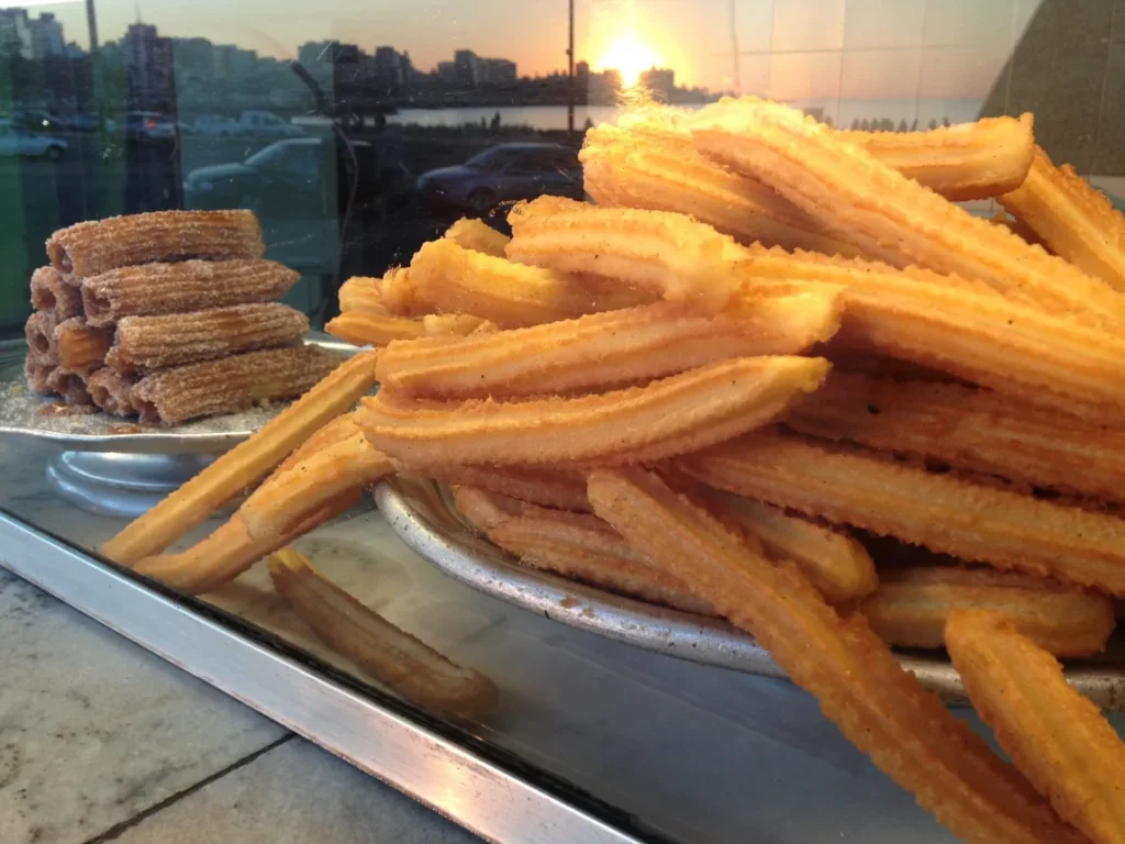 Churros longos e crocantes empilhados na bandeja de uma churreria