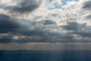 Mar sob ceu carregado com raios de sol atravessando as nuvens