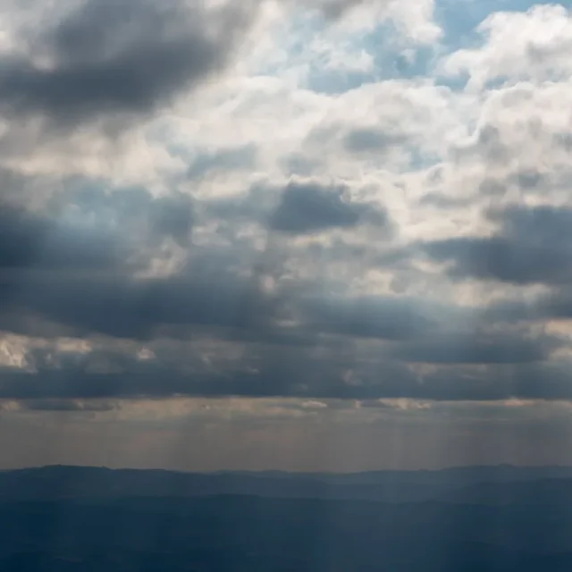 Mar sob ceu carregado com raios de sol atravessando as nuvens