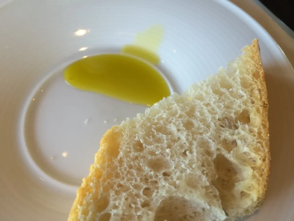 Azeite de oliva servido no prato ao lado de um pedaço de pão rústico