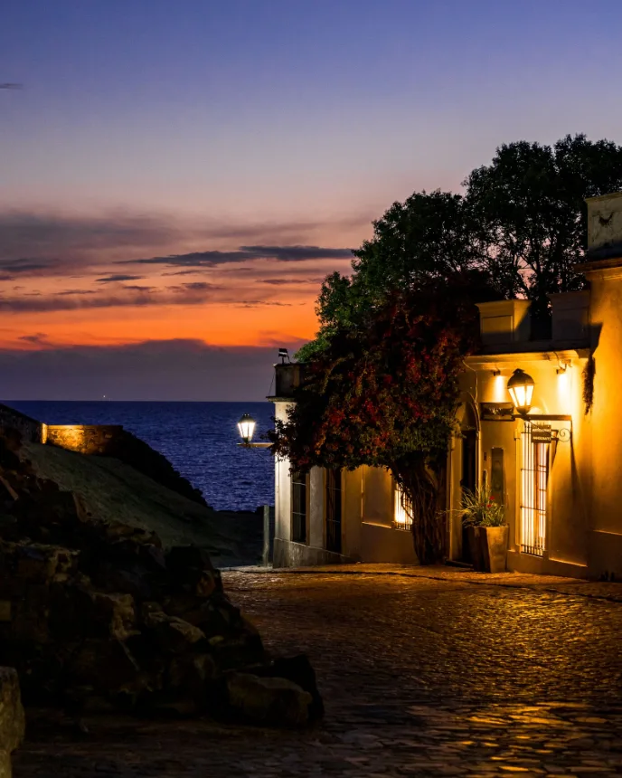Rua de pedra em Colonia del Sacramento ao entardecer, com o rio ao fundo