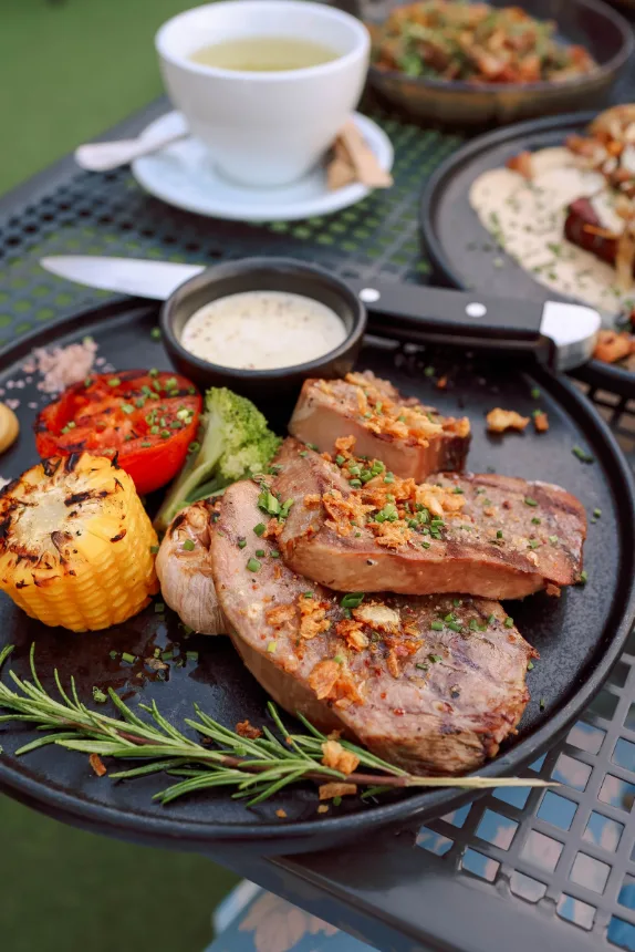 Mesa servida com carnes grelhadas, legumes e molhos para compartilhar