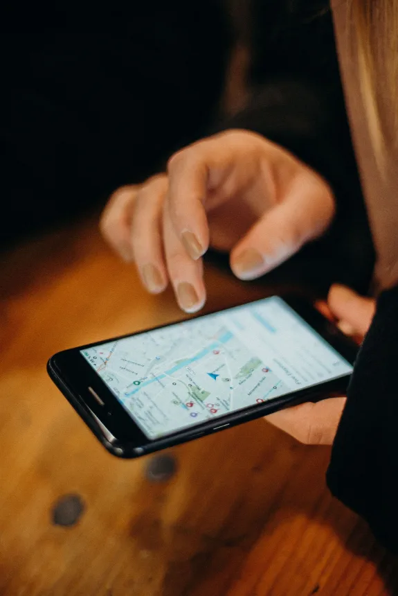 Pessoa consultando um mapa na tela do celular sobre uma mesa de madeira