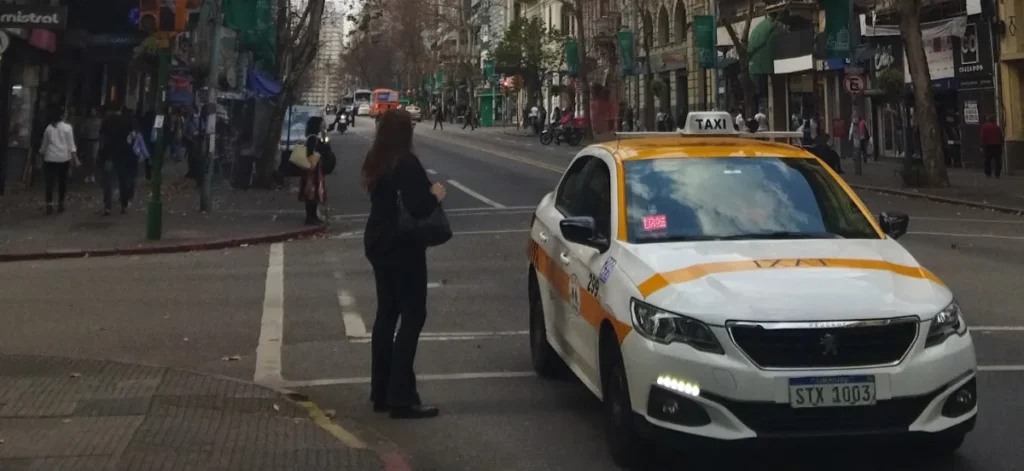 Taxi branco e amarelo parado na Avenida 18 de Julio, em Montevideo