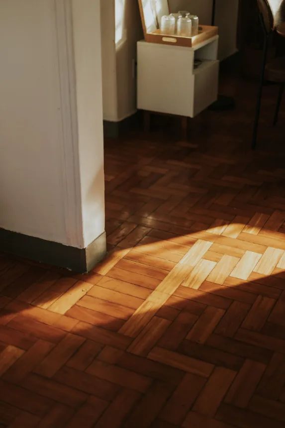 Piso de tacos de madeira iluminado pela luz que entra pela janela de uma casa antiga
