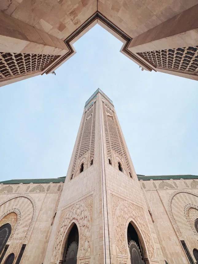 Torre de igreja vista de baixo, emoldurada por um arco de pedra
