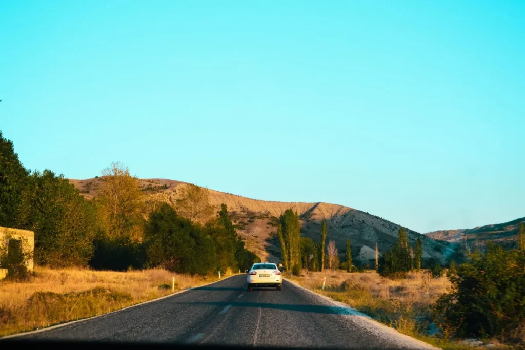 Carro em uma estrada rural cercada por colinas