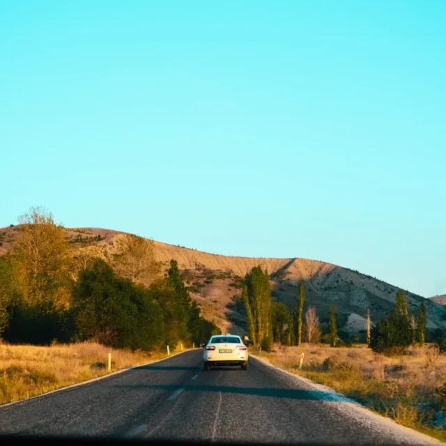 Carro em uma estrada rural cercada por colinas