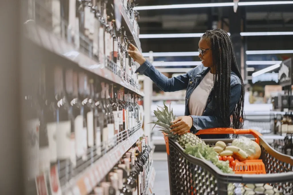 Mulher escolhendo uma garrafa de vinho no corredor de um supermercado