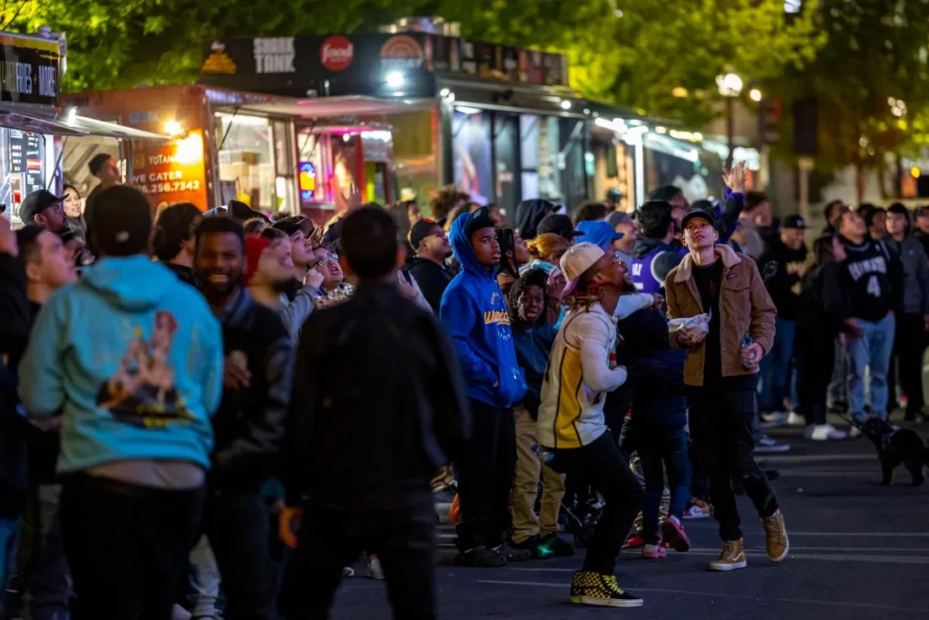Rua movimentada a noite com barracas de comida e publico circulando