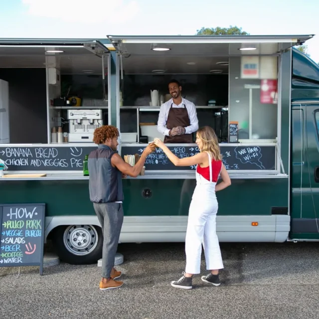 Food truck estacionado em area verde, com clientes fazendo o pedido no balcao