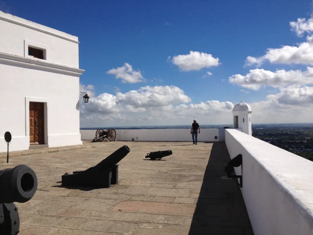 Pátio da fortaleza com canhões antigos e muralha branca sob o céu azul