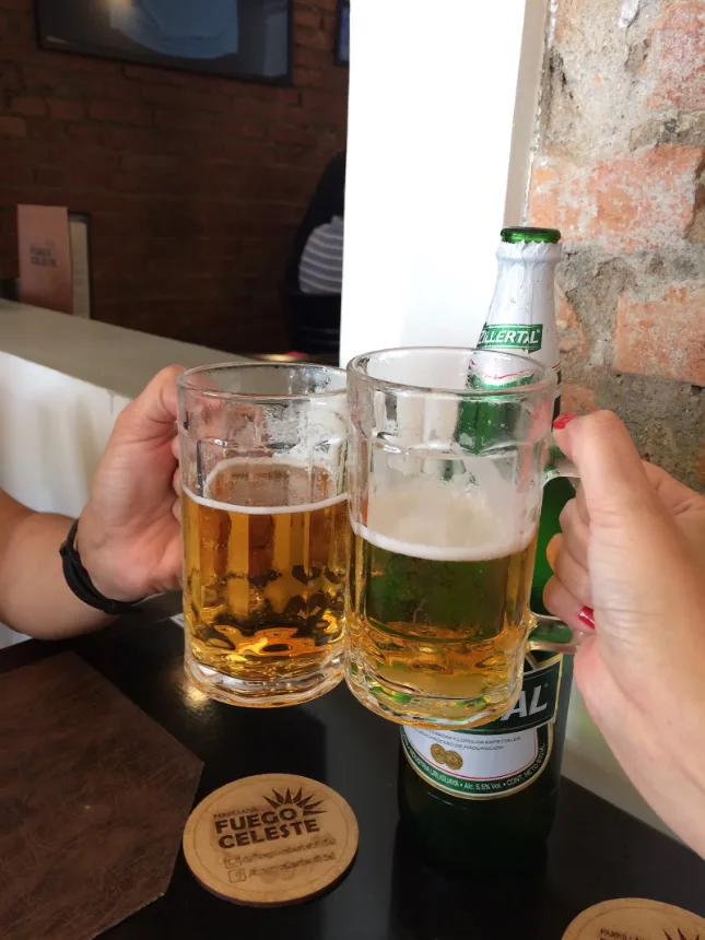 Brinde com canecas de chope na mesa do Fuego Celeste