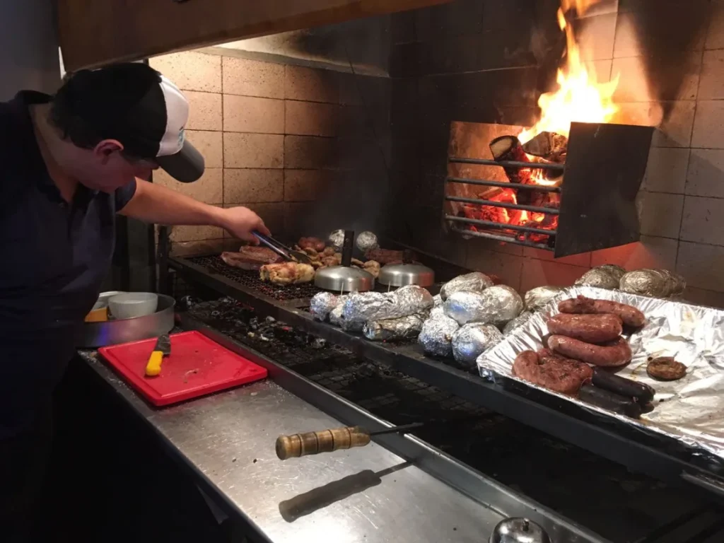 Parrillero virando as carnes na grelha do Fuego Celeste