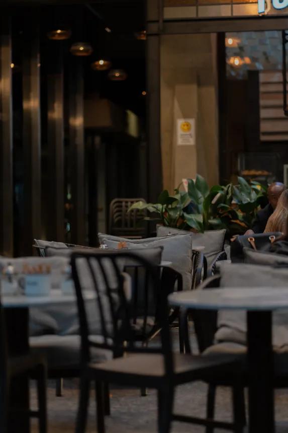 Mesas e poltronas de um café na calçada, sem clientes