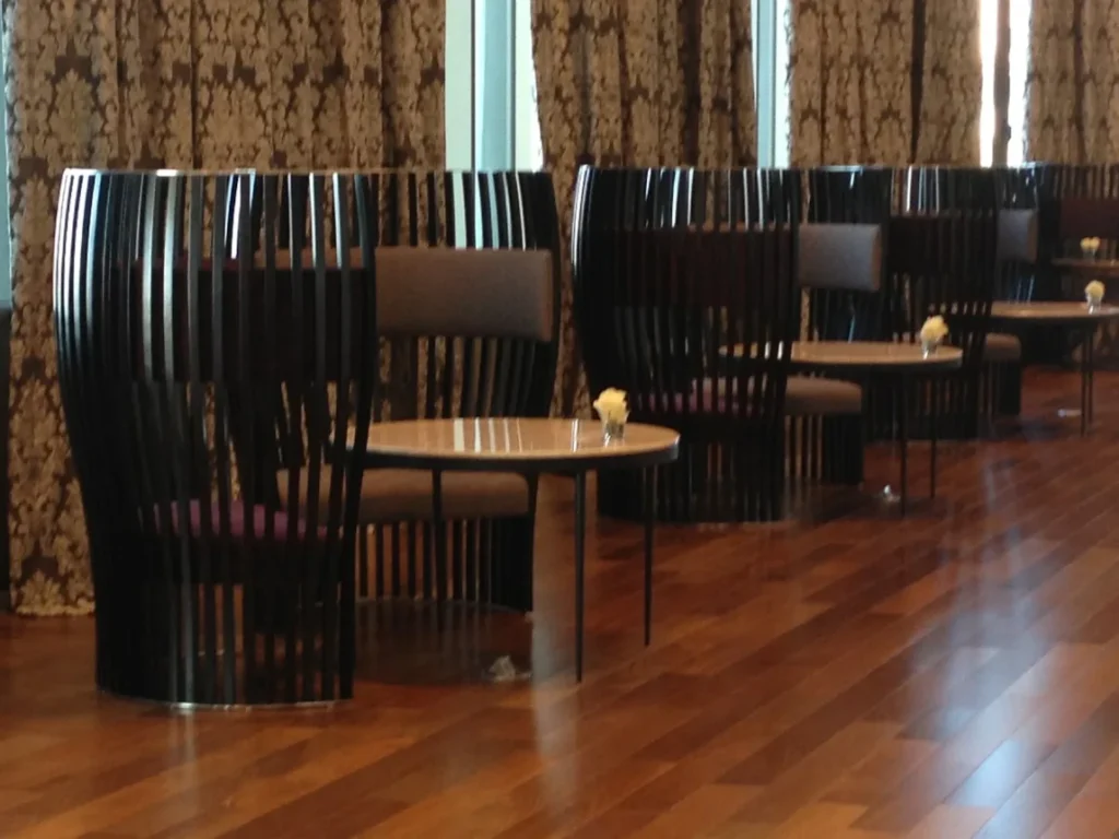 Salao interno do Hotel Casino Carrasco com mesas, poltronas e piso de madeira