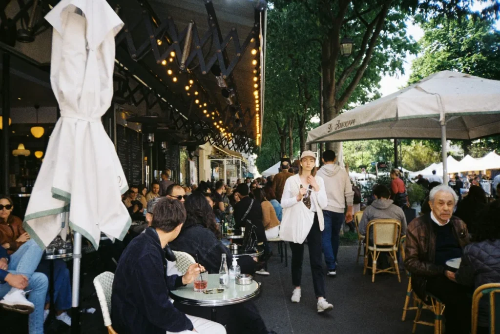 Esplanada de cafe com guarda-sois brancos e mesas na calcada, em clima parisiense