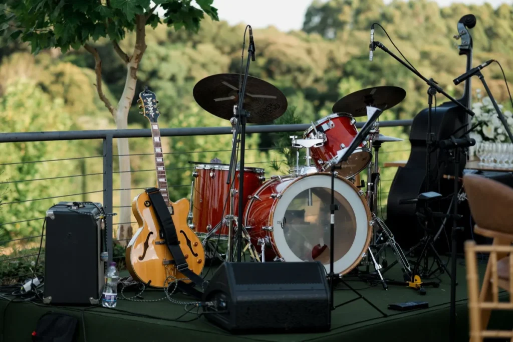 Palco ao ar livre com bateria e instrumentos montados entre as arvores