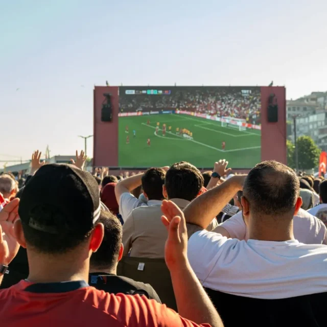 Multidao de torcedores assistindo a um jogo de futebol em telao ao ar livre