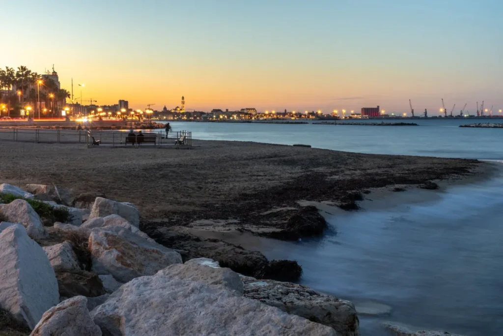 Costa rochosa ao entardecer com as luzes da cidade ao fundo