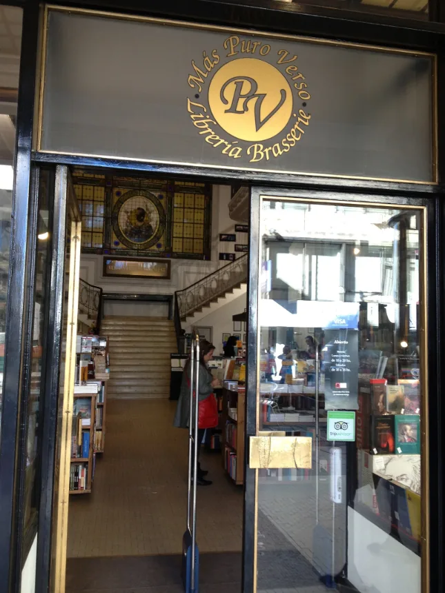 Entrada da Librería Puro Verso com letreiro dourado e escadaria ao fundo