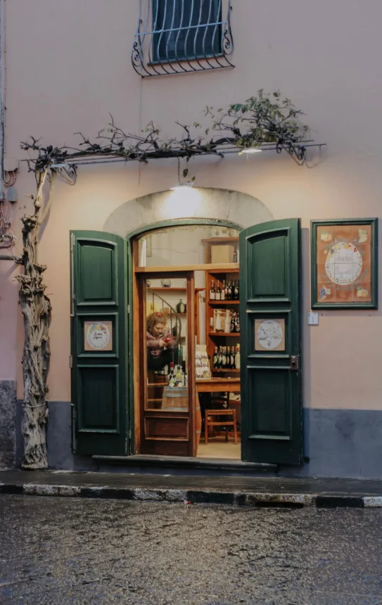 Entrada de loja de vinhos com portas verdes abertas