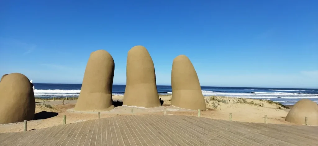 Dedos de concreto da escultura na areia com o mar ao fundo
