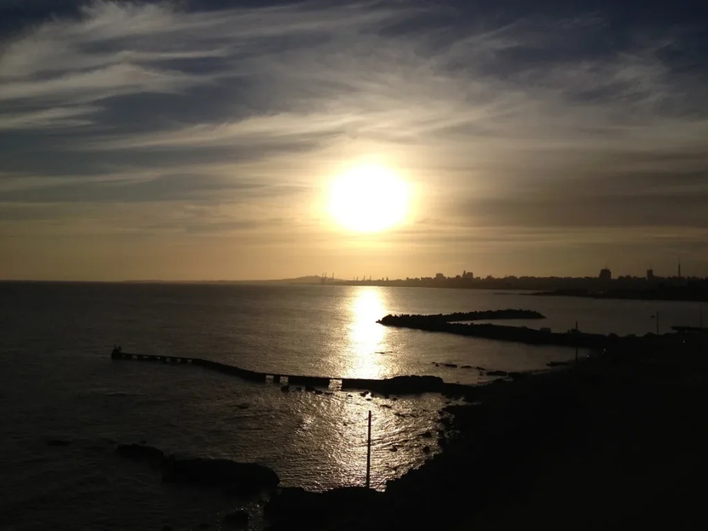 Vista da costa de Montevideo ao fim da tarde, com o sol baixo sobre a agua