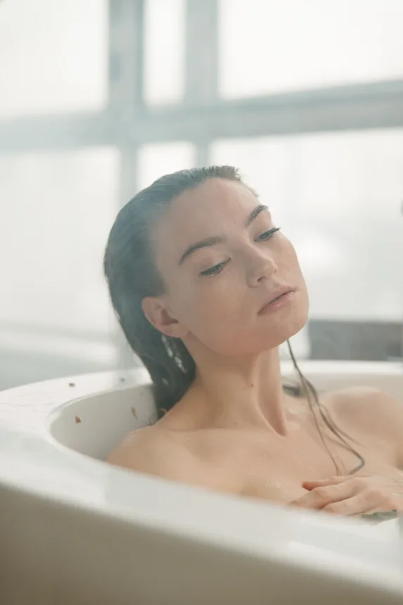 Pessoa relaxando de olhos fechados dentro de uma banheira de agua morna
