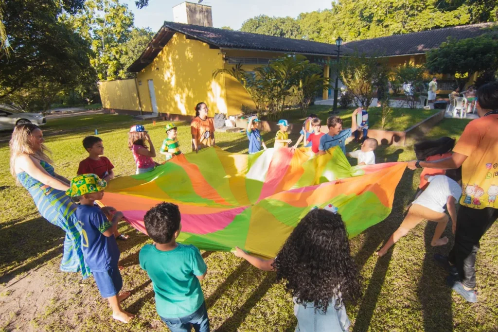 Criancas brincando ao ar livre com um paraquedas colorido em atividade recreativa