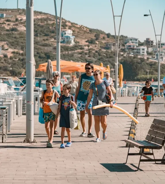 Família caminhando com crianças pelo calçadão à beira-mar