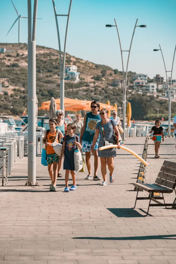 Família caminhando com crianças pelo calçadão à beira-mar