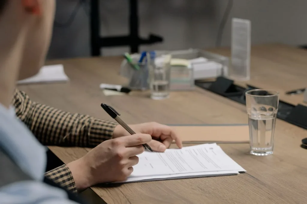 Pessoa assinando um contrato sobre uma mesa de madeira