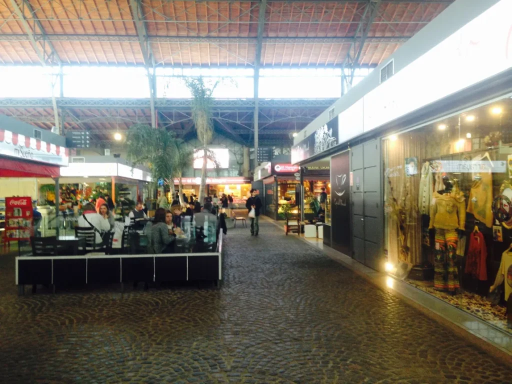 Corredor interno do Mercado Agricola com lojas e clientes