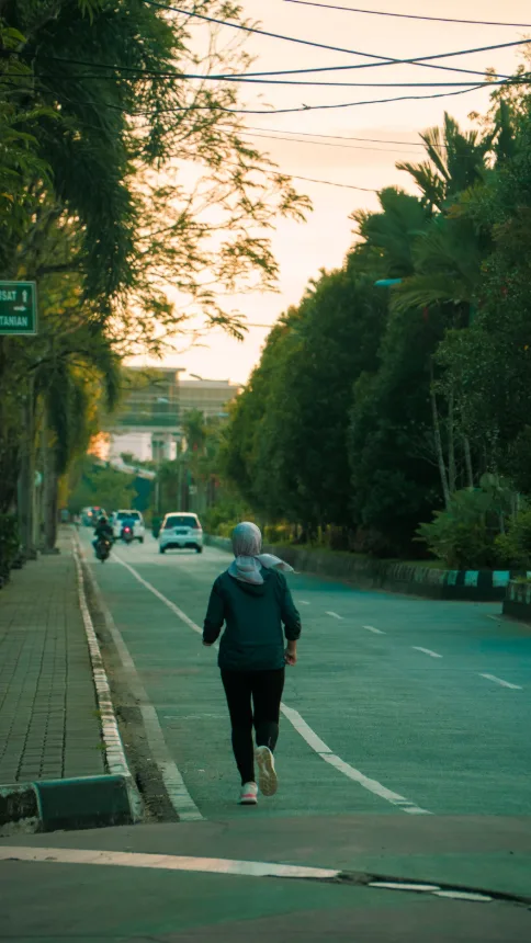 Pessoa correndo em uma via arborizada no fim da tarde