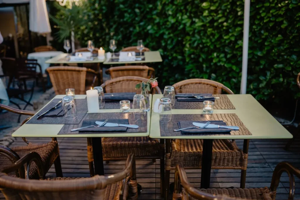 Mesas postas na area externa de um restaurante, prontas para o atendimento