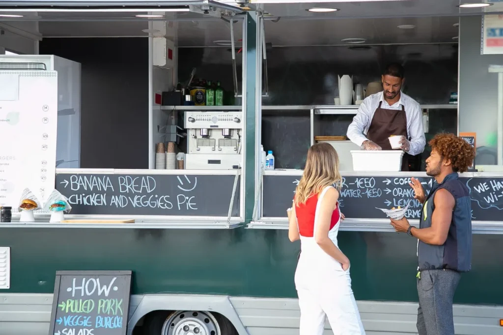 Balcao de um food truck com o cardapio escrito em giz e clientes esperando