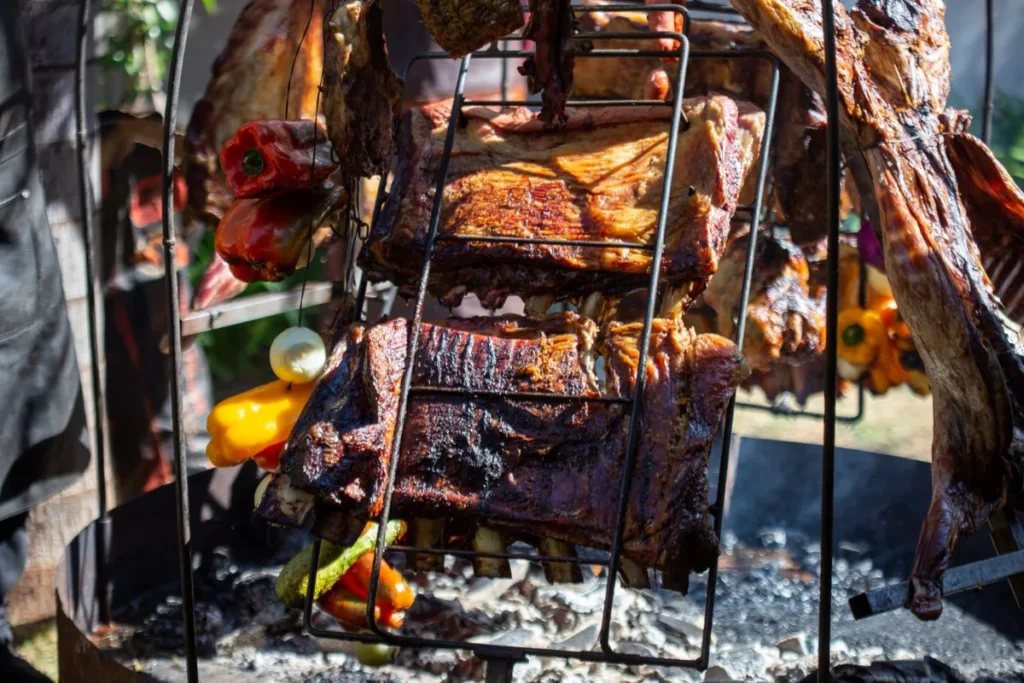 Carnes e legumes assando na grelha de uma parrilla