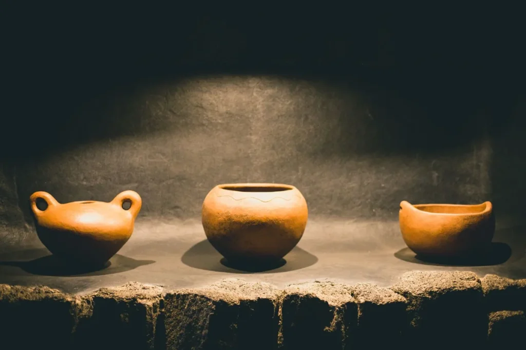 Três vasos de barro iluminados sobre fundo escuro