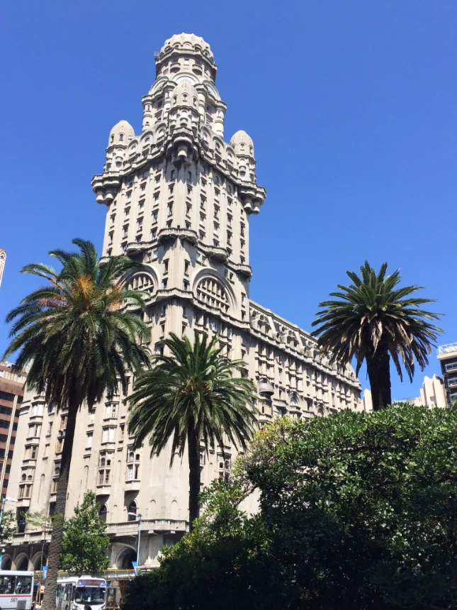 Torre do Palacio Salvo vista de baixo, emoldurada por palmeiras e ceu azul