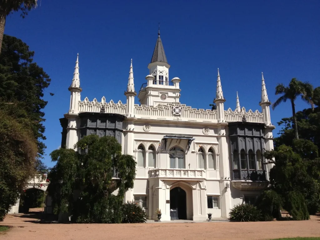 Edificio branco de estilo neogotico cercado por arvores no Parque del Prado