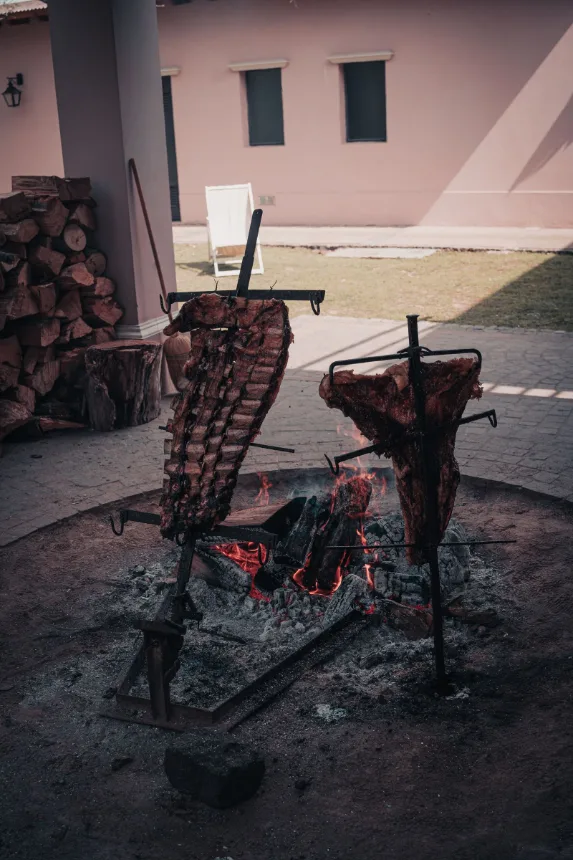 Costelas assando na cruz ao redor do fogo de chão
