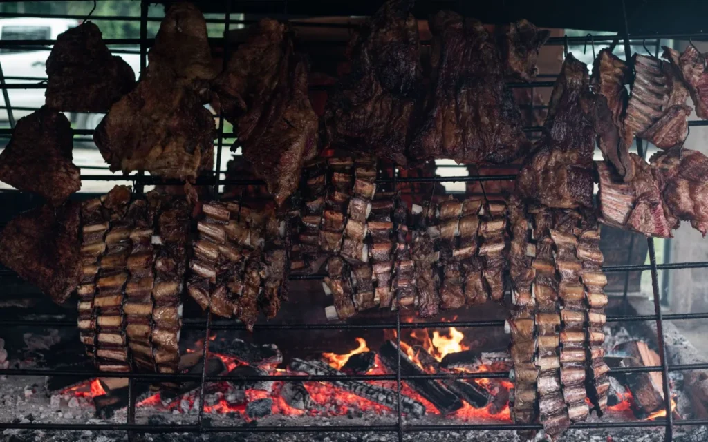 Grelha de parrilla carregada de cortes de carne sobre a brasa