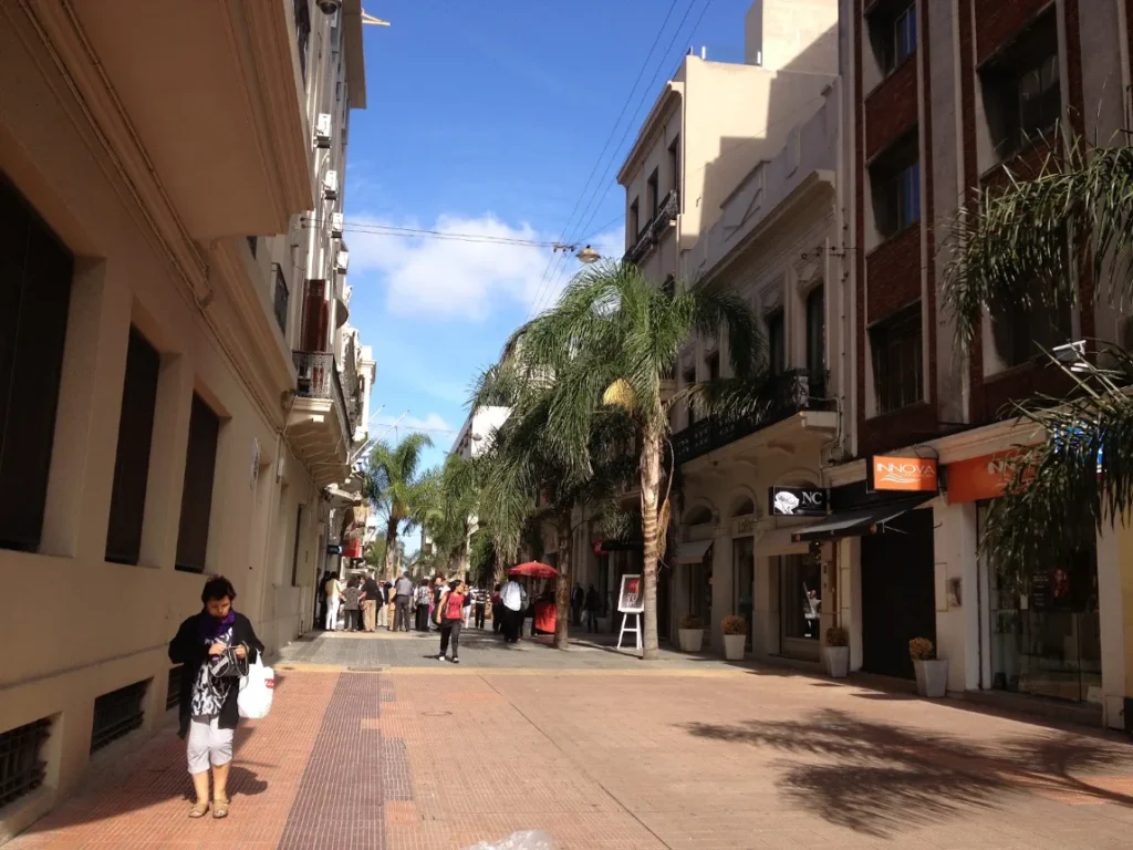 Peatonal Sarandi com pedestres, palmeiras e fachadas antigas da Ciudad Vieja