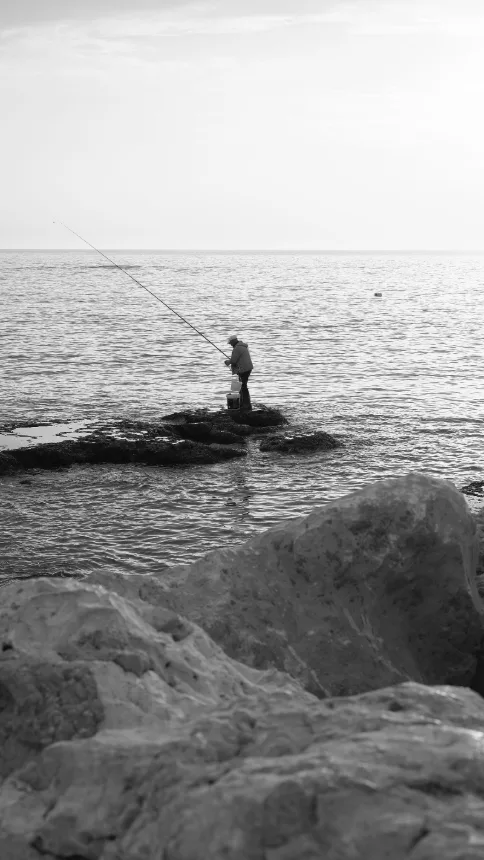 Pescador solitario sobre as rochas da costa de Punta Colorada, no Uruguai
