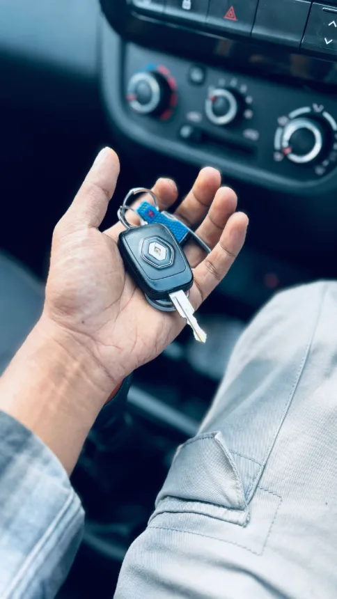 Mao segurando a chave dentro de um carro, com o painel ao fundo