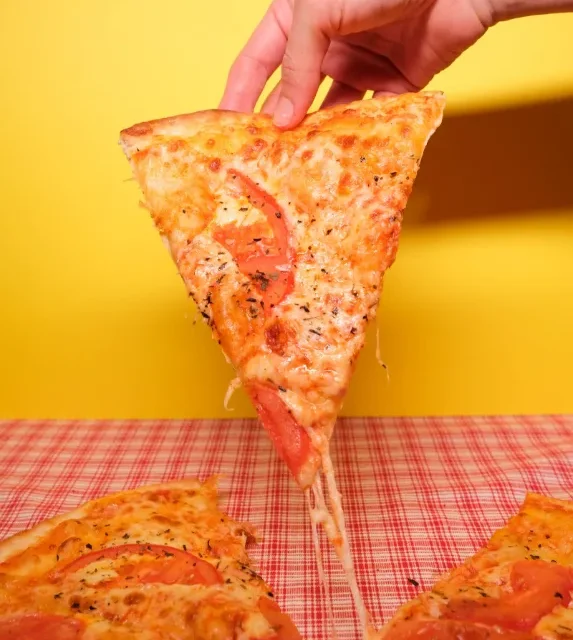 Fatia de pizza de muçarela com tomate vista de cima sobre fundo amarelo