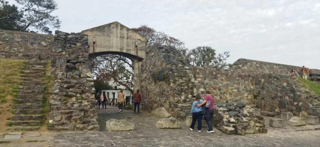 Turistas fotografando junto ao arco e à muralha de pedra da Porta do Campo